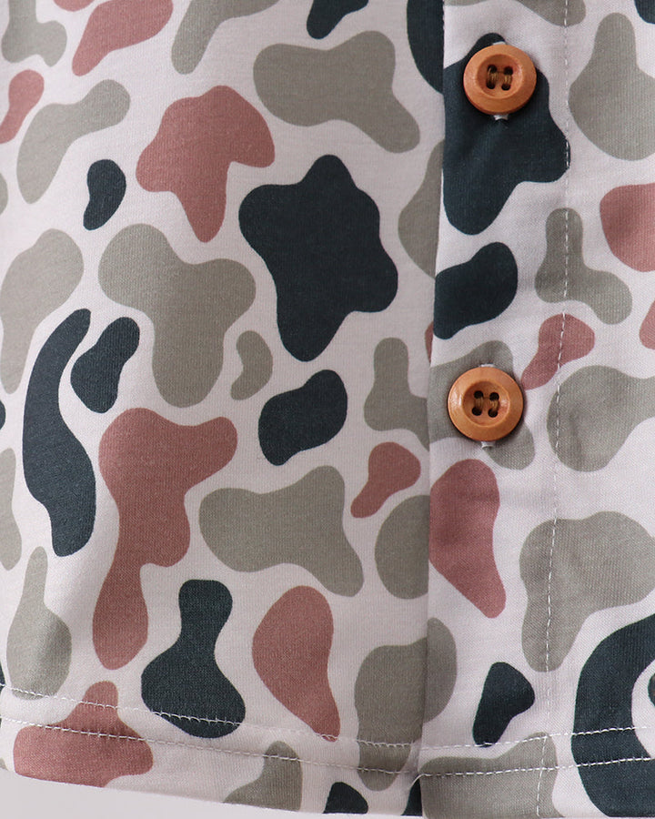 Close-up of a shirt with a camouflage pattern and wooden buttons on a white background