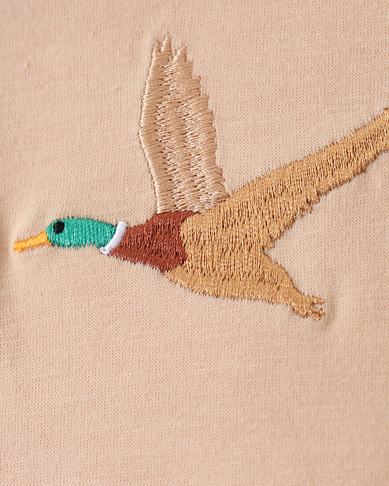 Embroidered duck design on a beige fabric background