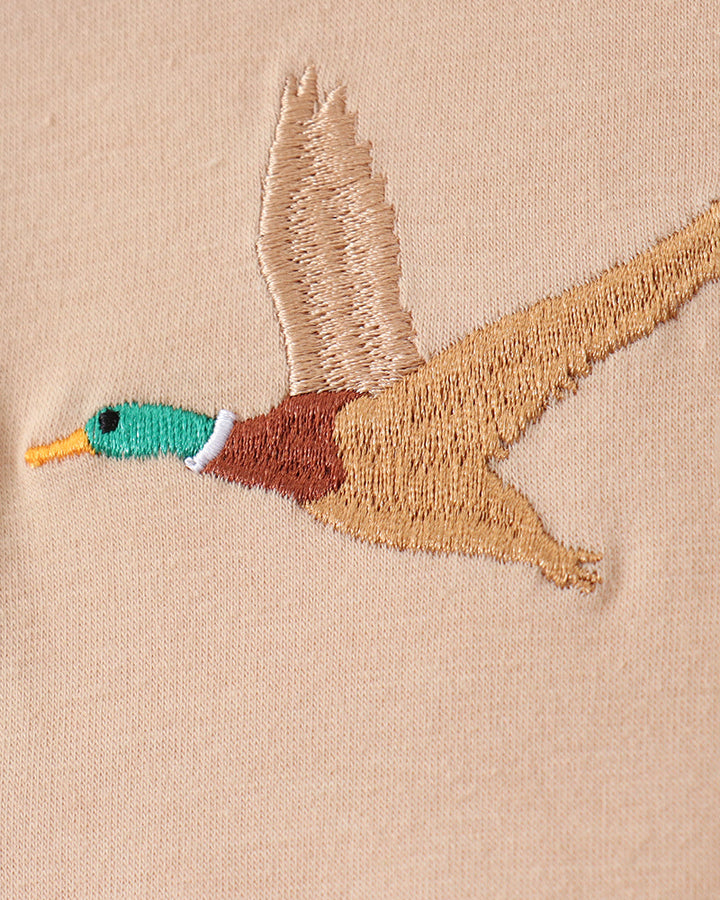 Embroidered duck design on a beige fabric background