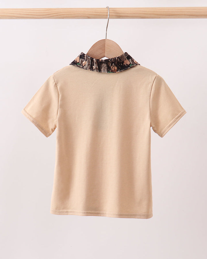 Beige shirt with floral collar on a wooden hanger against a white background