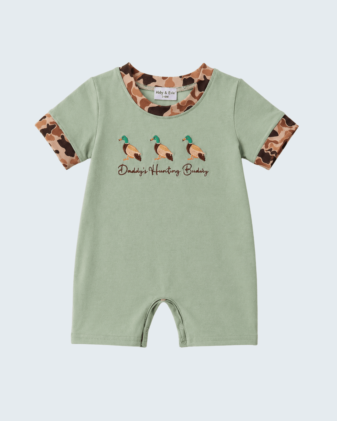 Green baby romper with camouflage sleeves and duck design on a light gray background