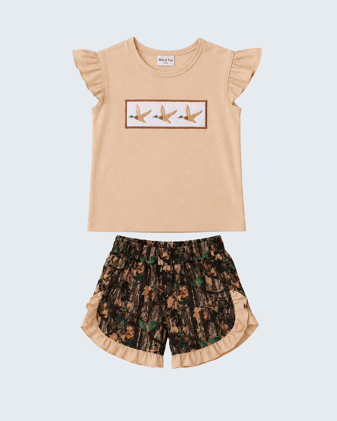 Beige top with ruffled sleeves and floral shorts on a light gray background