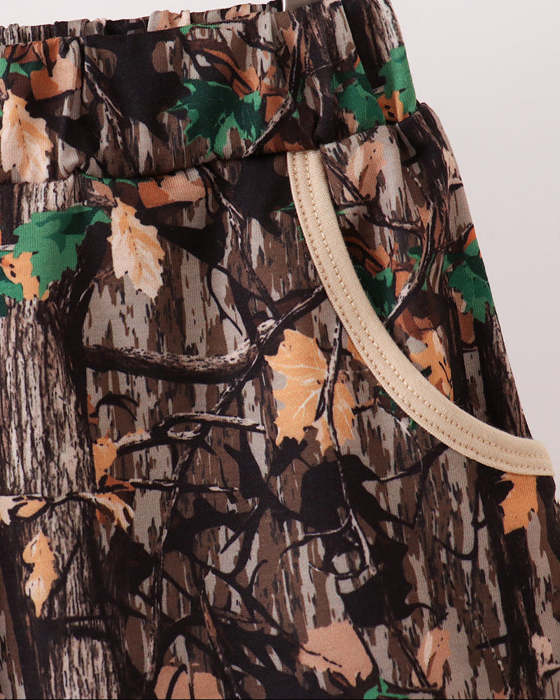 Camouflage-patterned shorts with drawstring on a hanger against a white background