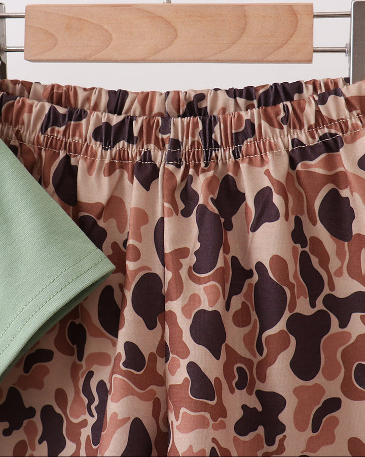 Camouflage-patterned pants on a hanger against a white background