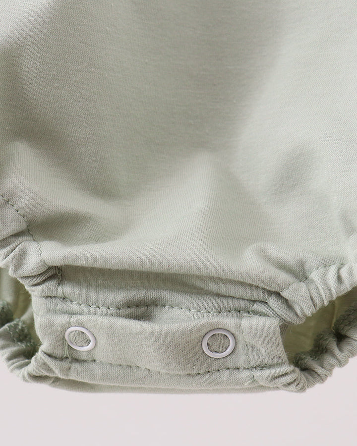 Close-up of a green romper on a light gray background