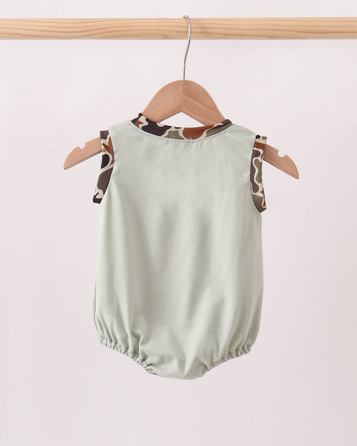 Light green baby romper with animal print straps on a wooden hanger against a white background