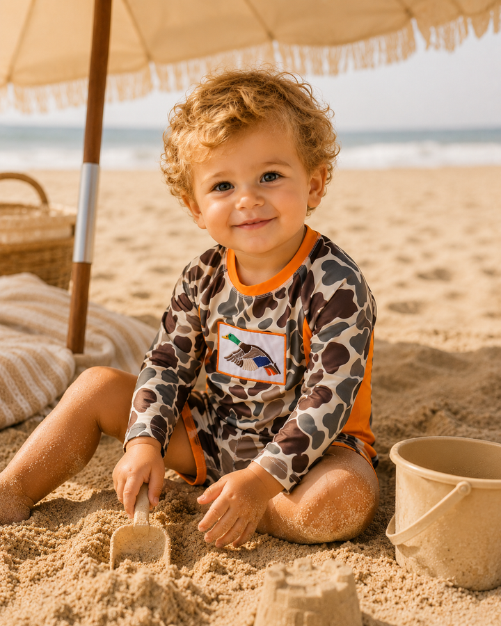 Child playing in the sand on a beach with an umbrella and bucket in the background