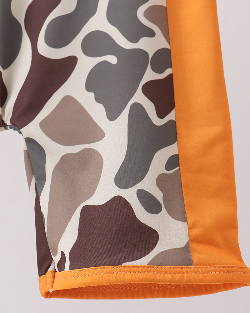 Close-up of a garment with a camouflage pattern and orange border on a light gray background