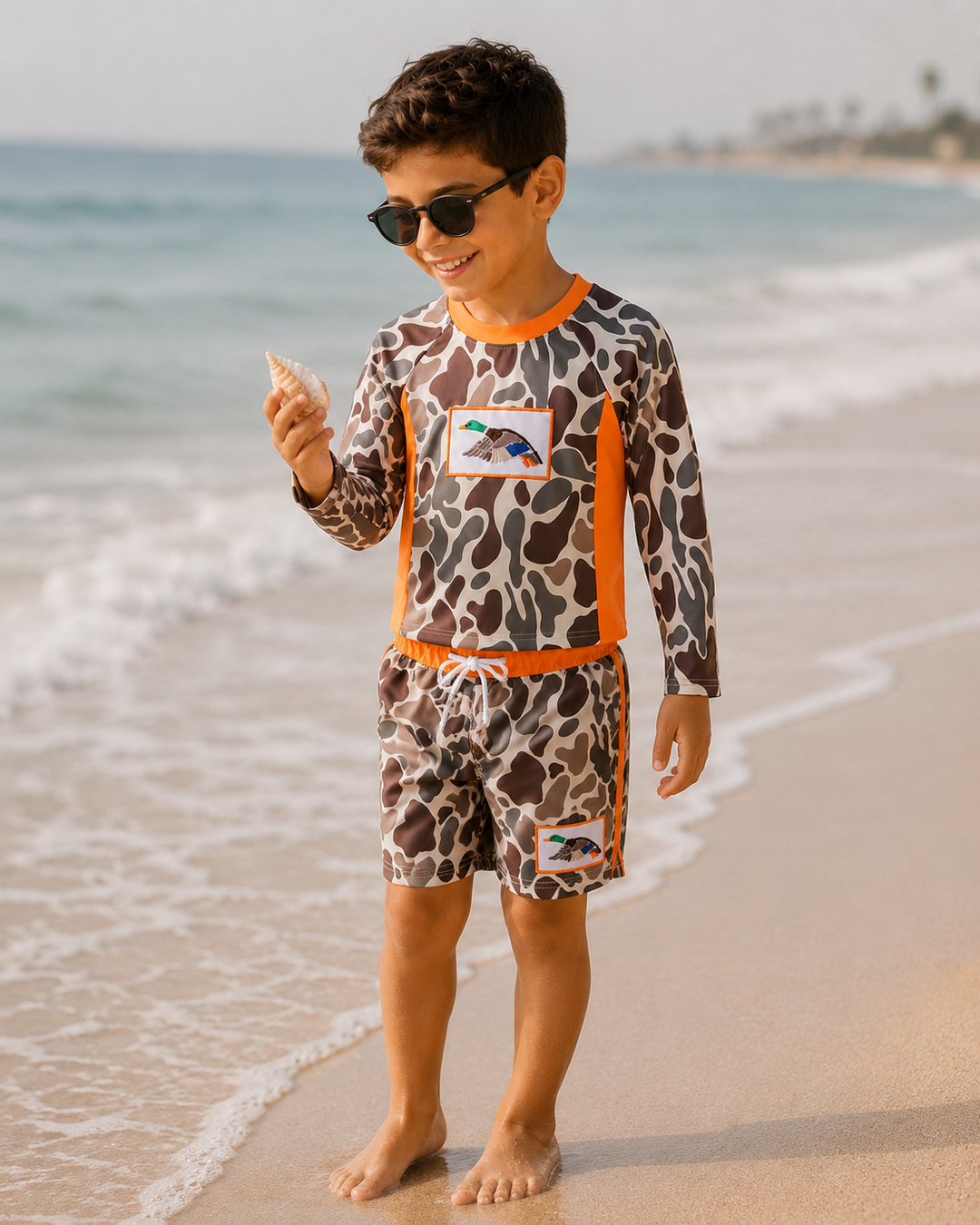 Child in leopard print swimsuit with orange accents on a beach
