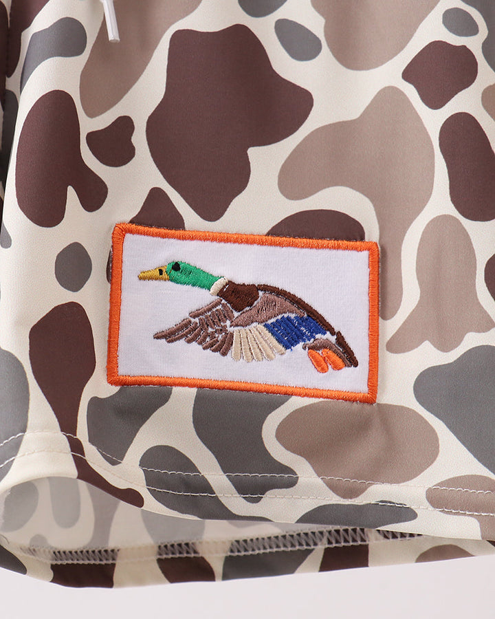 Camouflage-patterned fabric with a embroidered duck patch on a white background