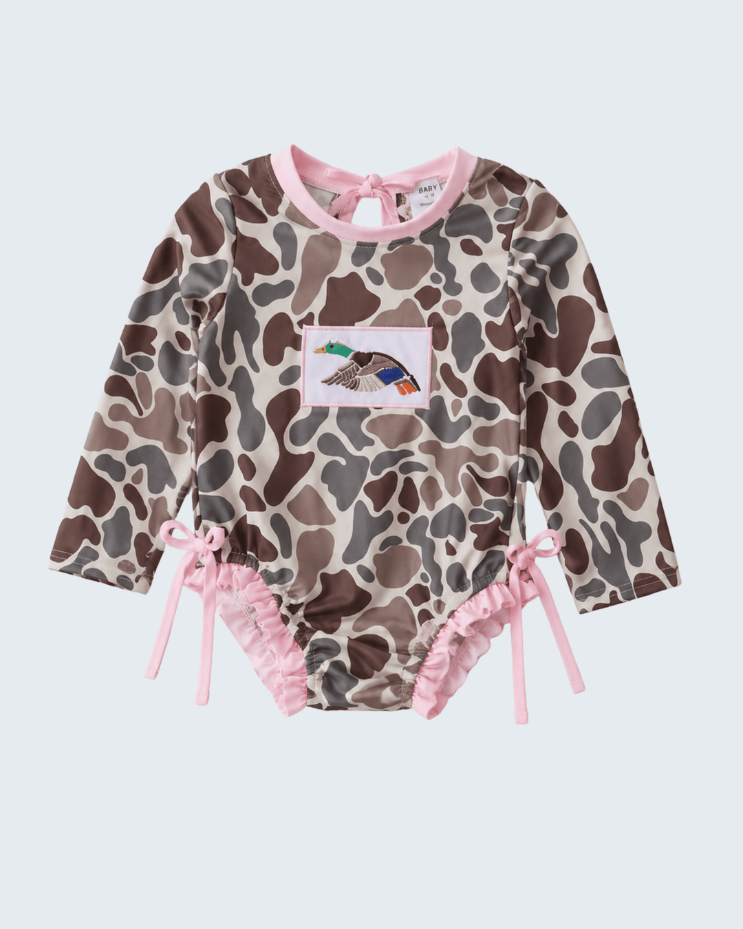 Camouflage-patterned rashguard with pink accents on a light gray background