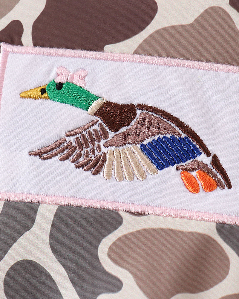 Embroidered duck design on a fabric with a camouflage pattern
