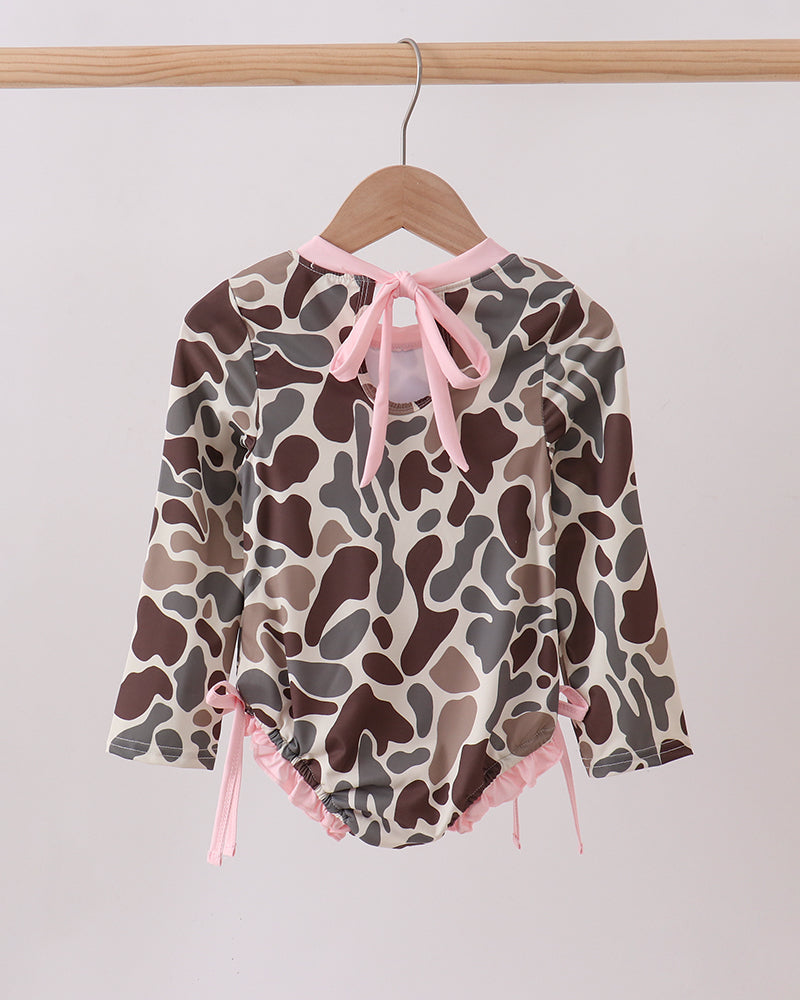 Camouflage-patterned baby romper with pink accents on a hanger against a white background