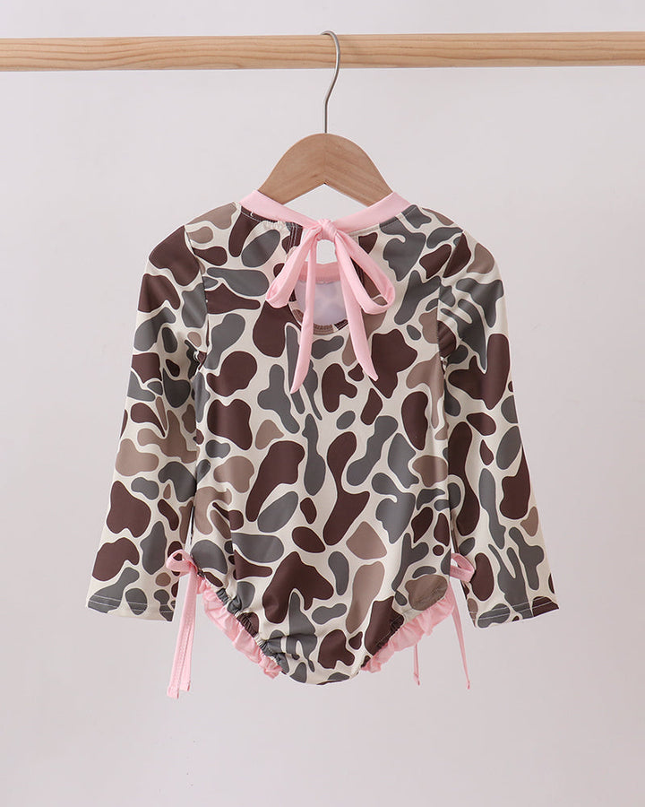 Camouflage-patterned baby romper with pink accents on a hanger against a white background