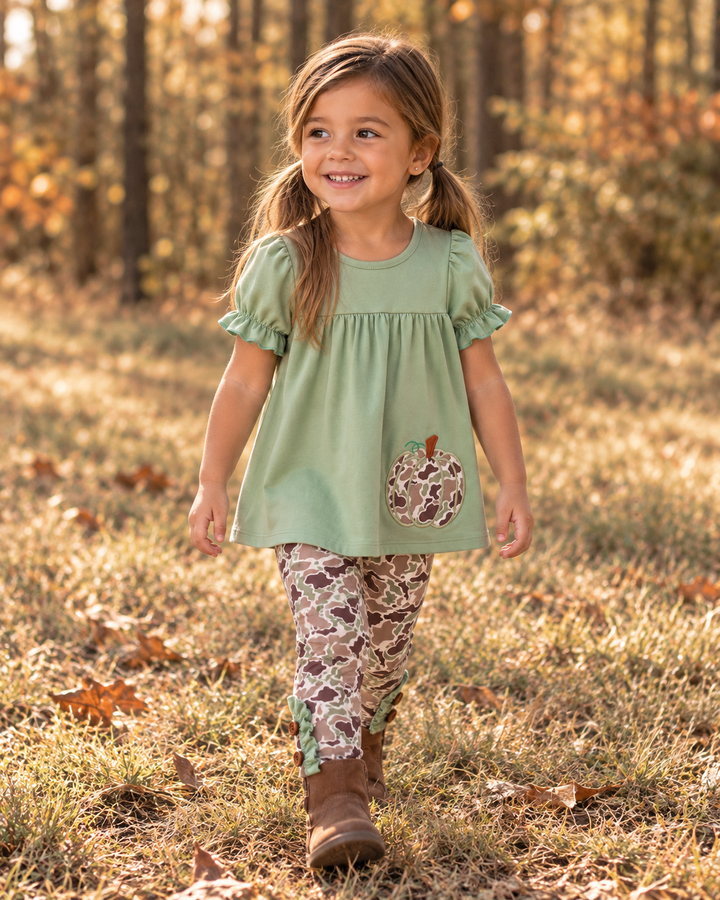 Young girl in camo print outfit walking by the edge of the woods