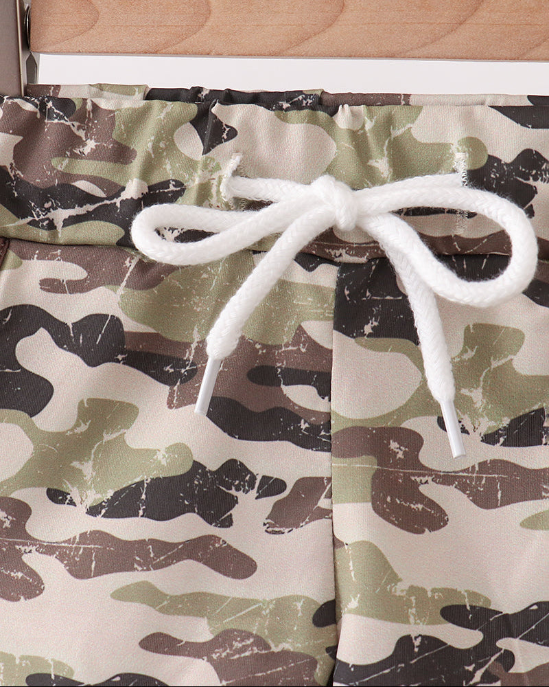 Camouflage shorts with a white drawstring on a wooden surface