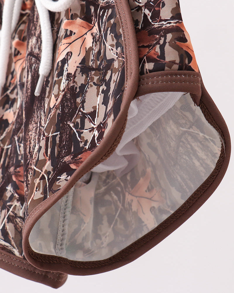 Camouflage-patterned swim trunks with brown trim on a white background