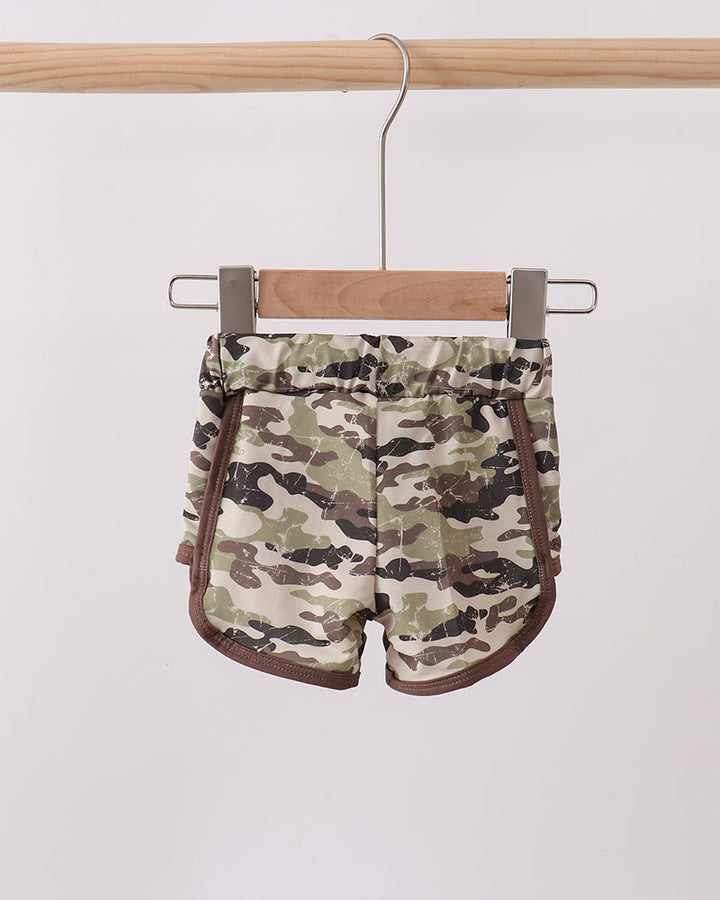 Camouflage shorts hanging on a wooden hanger against a white background