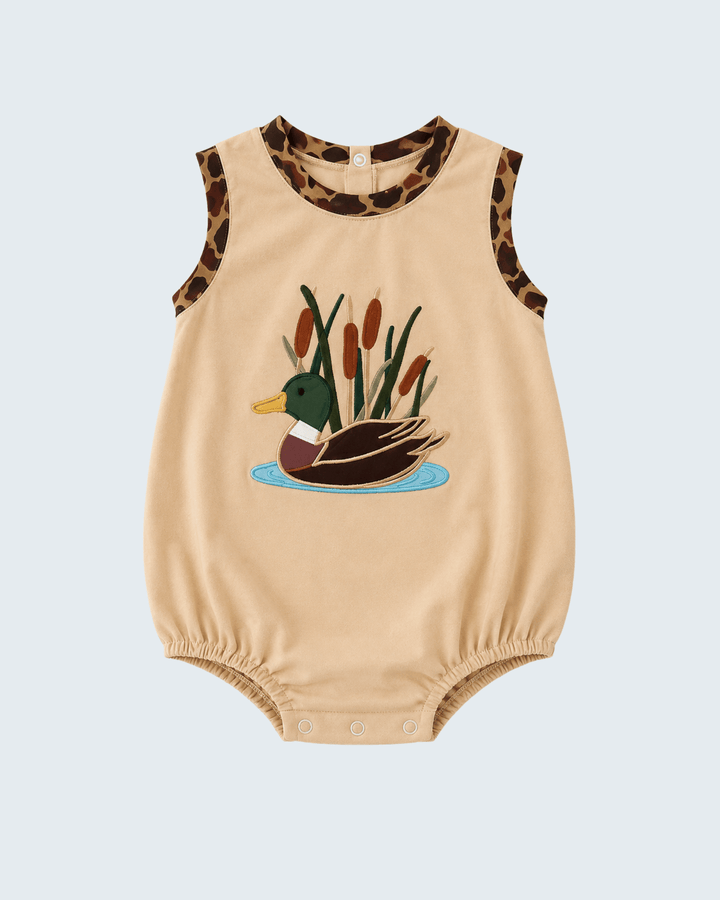 A sleeveless beige baby romper with a duck and cattails graphic on the front, leopard-print trim at the neckline and armholes, and snap closures at the crotch.