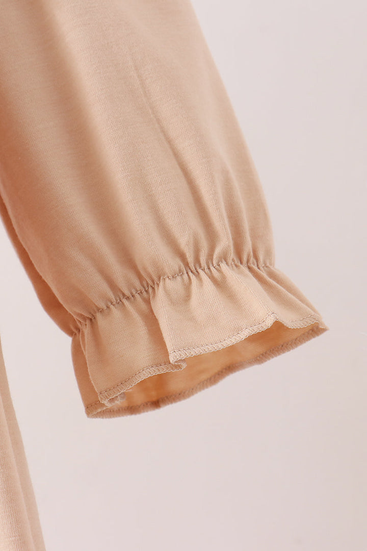 Close-up of a beige or light tan fabric garment sleeve with gathered elastic cuffs and a ruffled hem, shown against a plain light background.