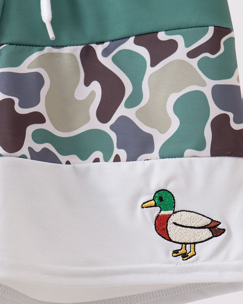 Close-up of a camouflage-patterned fabric with a duck embroidery on a white background