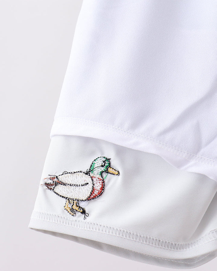 Close-up of a white shirt cuff with a colorful embroidered duck design on a light gray background.