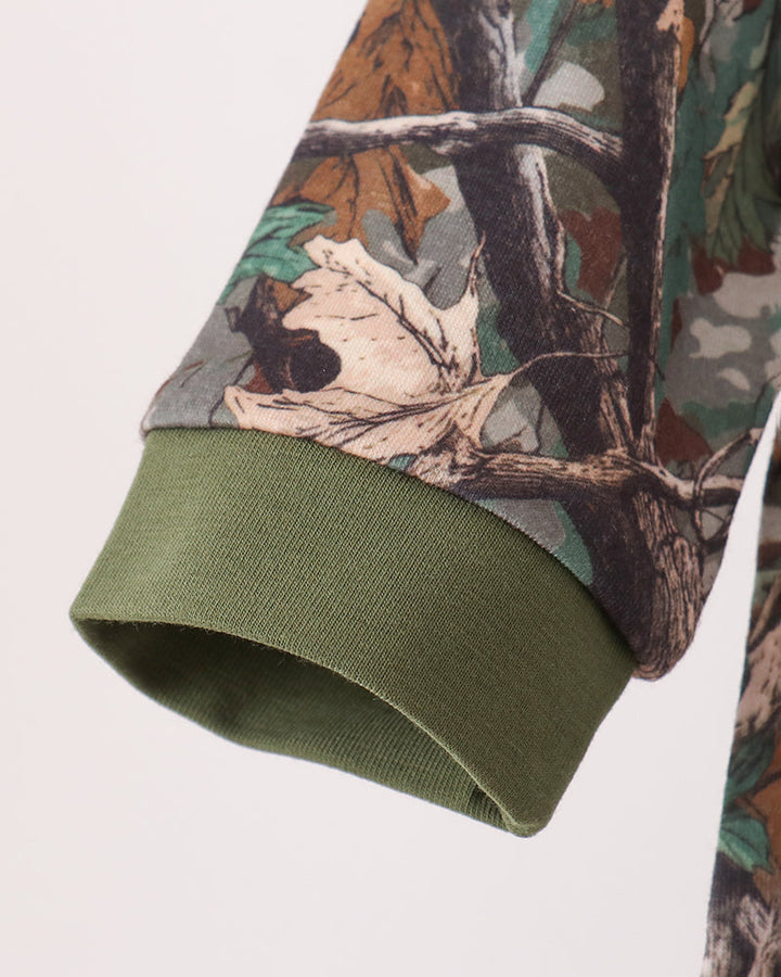 Close-up of a camouflage-patterned long-sleeve garment sleeve with an olive green ribbed cuff, shown against a plain light background.