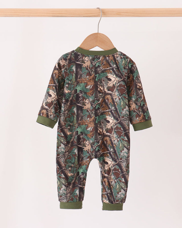 A baby camouflage jumpsuit hanging on a wooden hanger against a plain light background.
