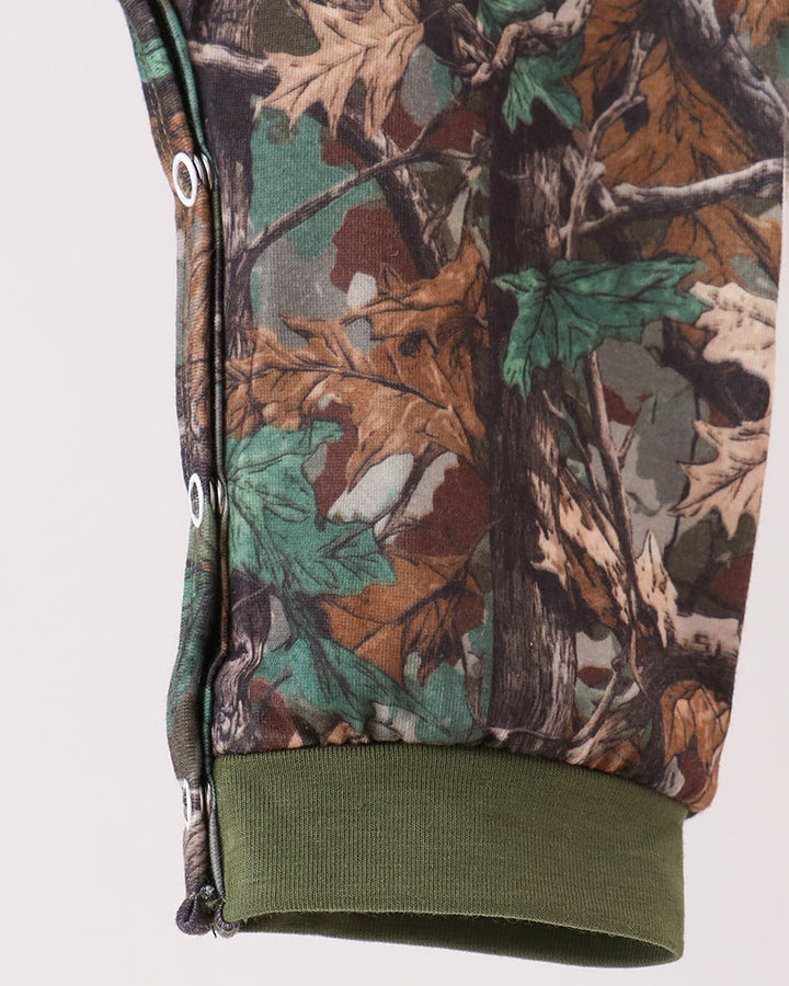Close-up of a camouflage-patterned garment sleeve with an olive green ribbed cuff, shown against a plain light background.