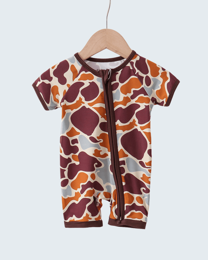 Baby romper with animal print on a hanger against a white background