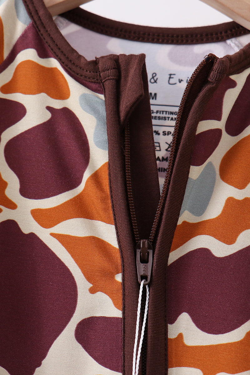 Close-up of a patterned garment with a zipper, featuring brown, orange, and purple colors.