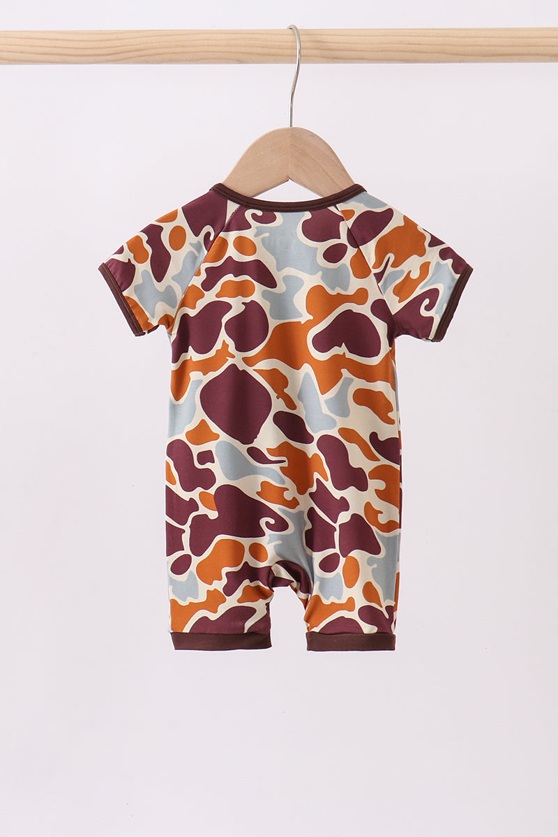 Baby romper with a colorful pattern on a wooden hanger against a white background