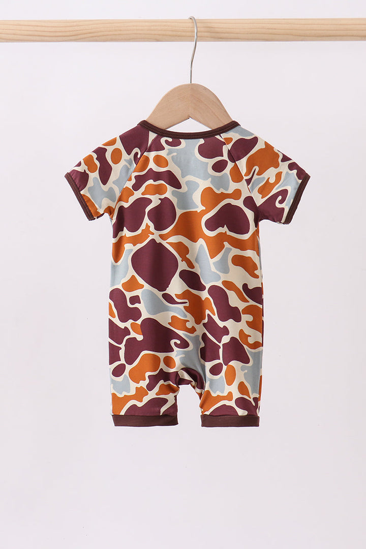 Baby romper with a colorful pattern on a wooden hanger against a white background