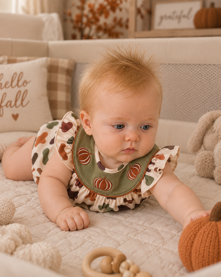 Baby girl in a camp romper is in her playpin.