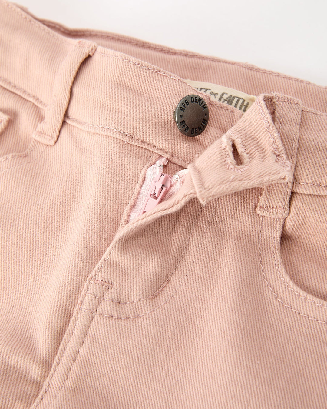 Light pink girls cargo pants close-up of waistband button and inner label