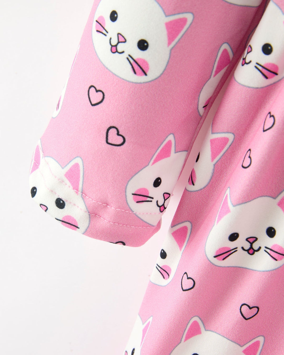 Pink fabric with white cat faces and black hearts on a white background