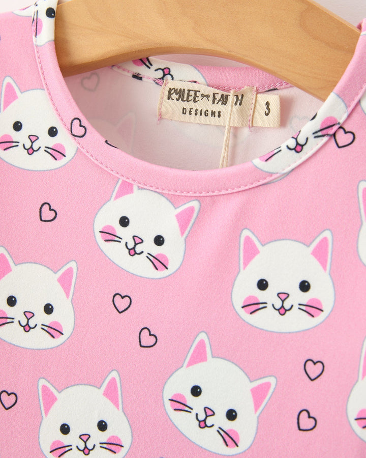 Pink shirt with cat prints and heart shapes on a wooden hanger
