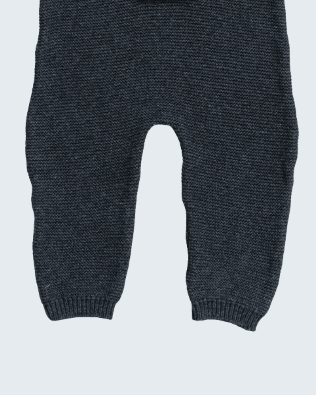 Close-up of a pair of dark charcoal gray knit pants with ribbed ankle cuffs, shown against a light gray background.