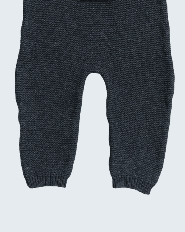 Close-up of a pair of dark charcoal gray knit pants with ribbed ankle cuffs, shown against a light gray background.