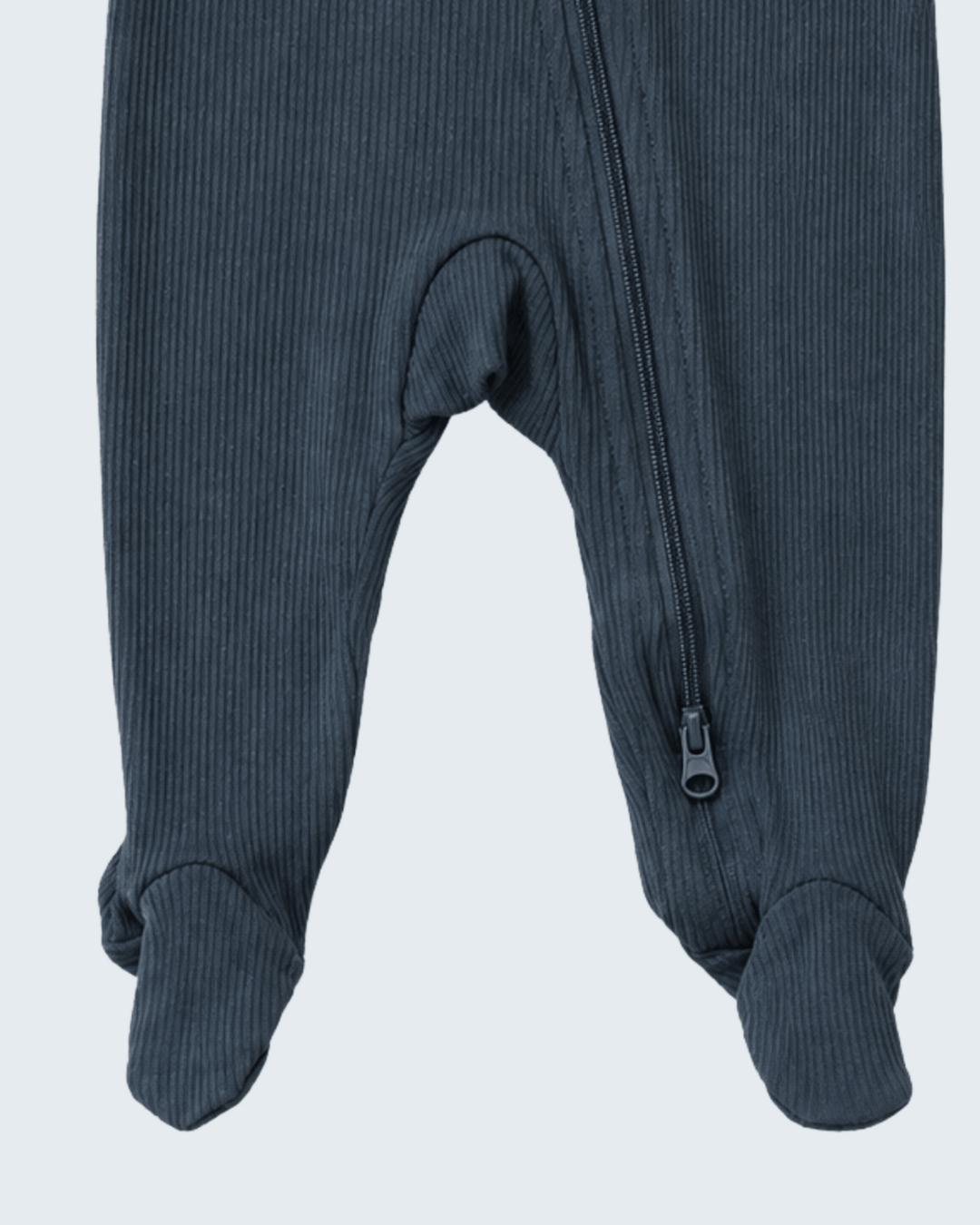 Close-up of a ribbed footed one-piece garment in a dark slate blue-gray color, showing the zipper and foot cuffs against a light gray background.