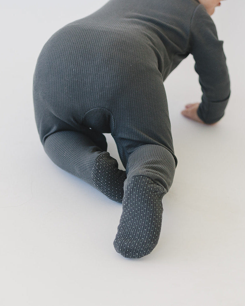 Charcoal ribbed cotton zipper romper on baby, kneeling pose with covered foot