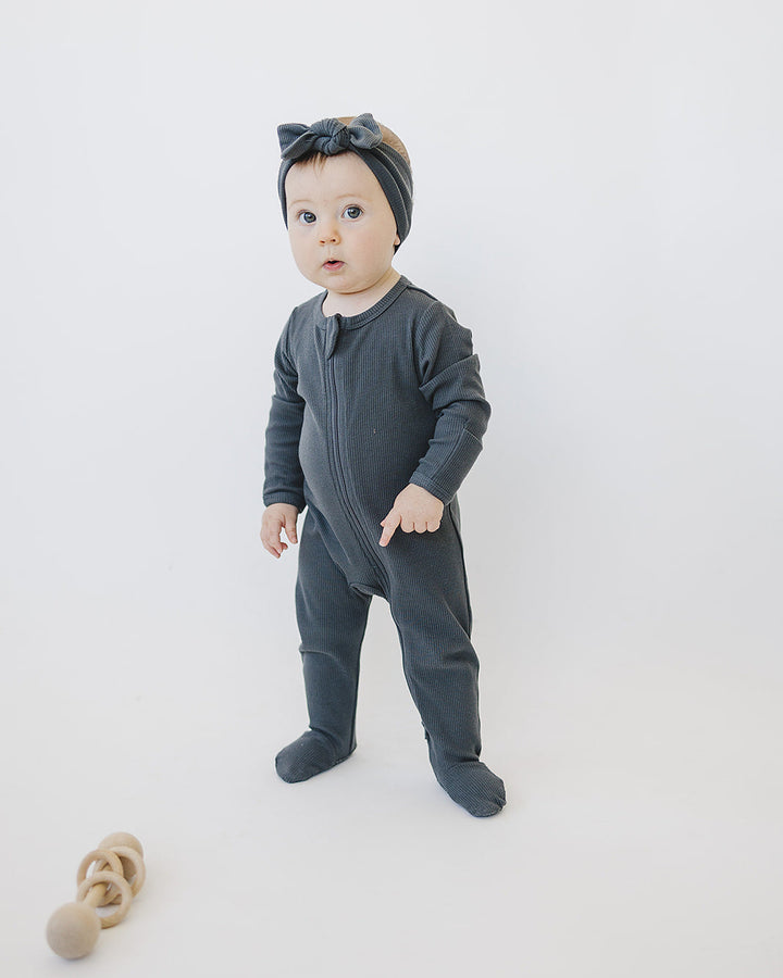 Charcoal ribbed cotton zipper romper on baby, standing pose, long-sleeve footed legs