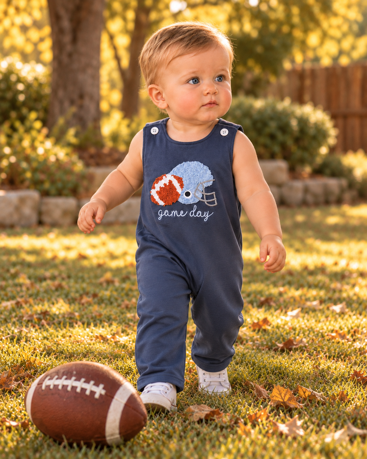 Toddler wearing navy sleeveless football game day romper with helmet applique
