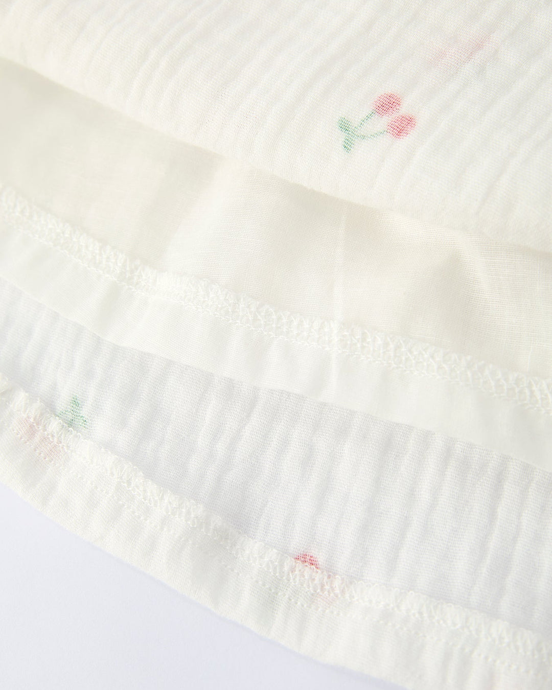 White fabric with embroidered pink flowers on a white background