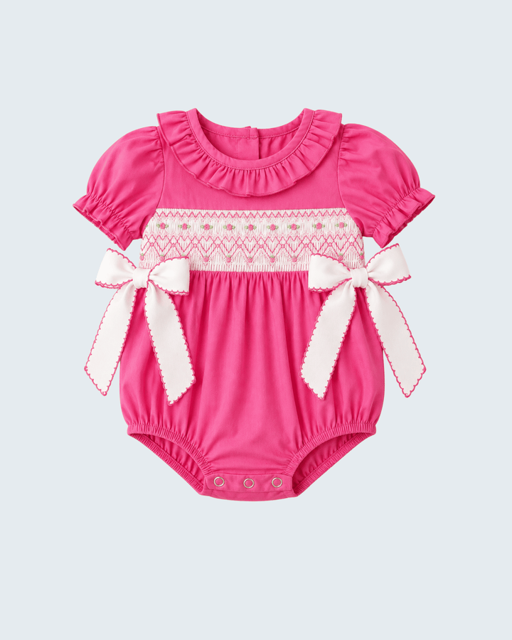 Hot pink smocked romper with ruffled neckline and white bow ties, short sleeves
