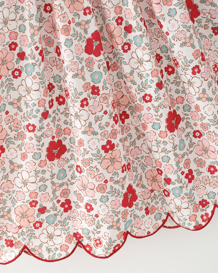 Girls floral dress fabric close-up with red scalloped trim hem