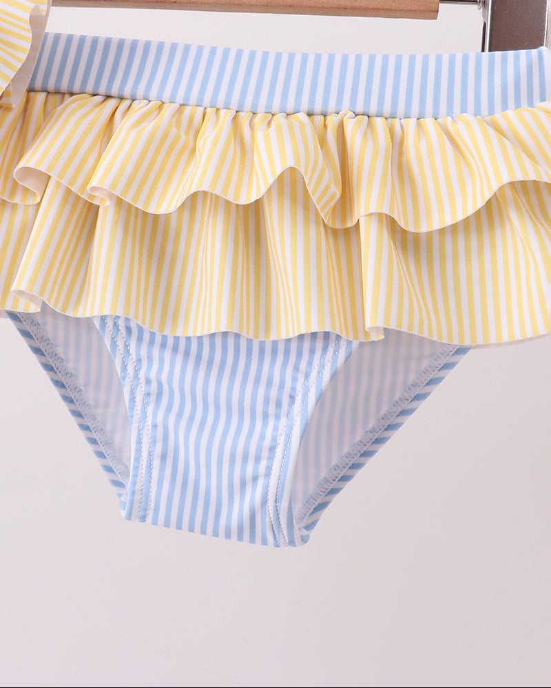 Yellow and blue striped ruffled swim bottoms on a hanger against a white background