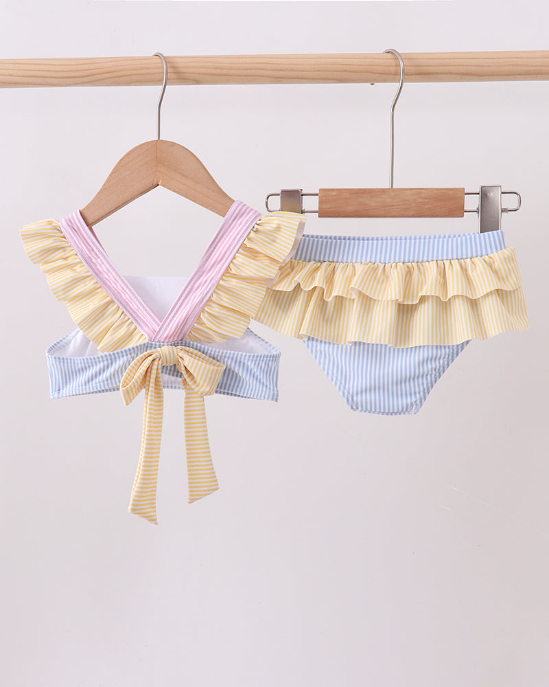 Pair of colorful ruffled bikini bottoms hanging on a wooden rack against a light background