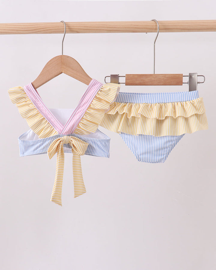 Pair of colorful ruffled bikini bottoms hanging on a wooden rack against a light background