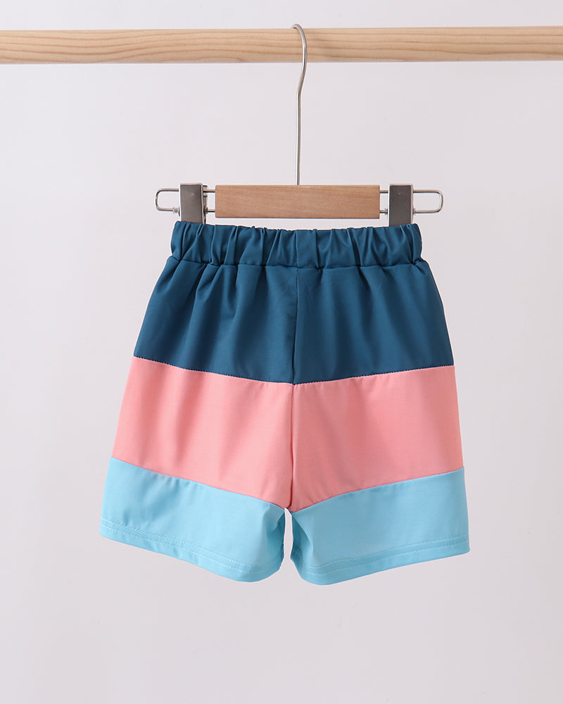 Color-blocked shorts with blue, pink, and light blue design on a hanger against a white background.